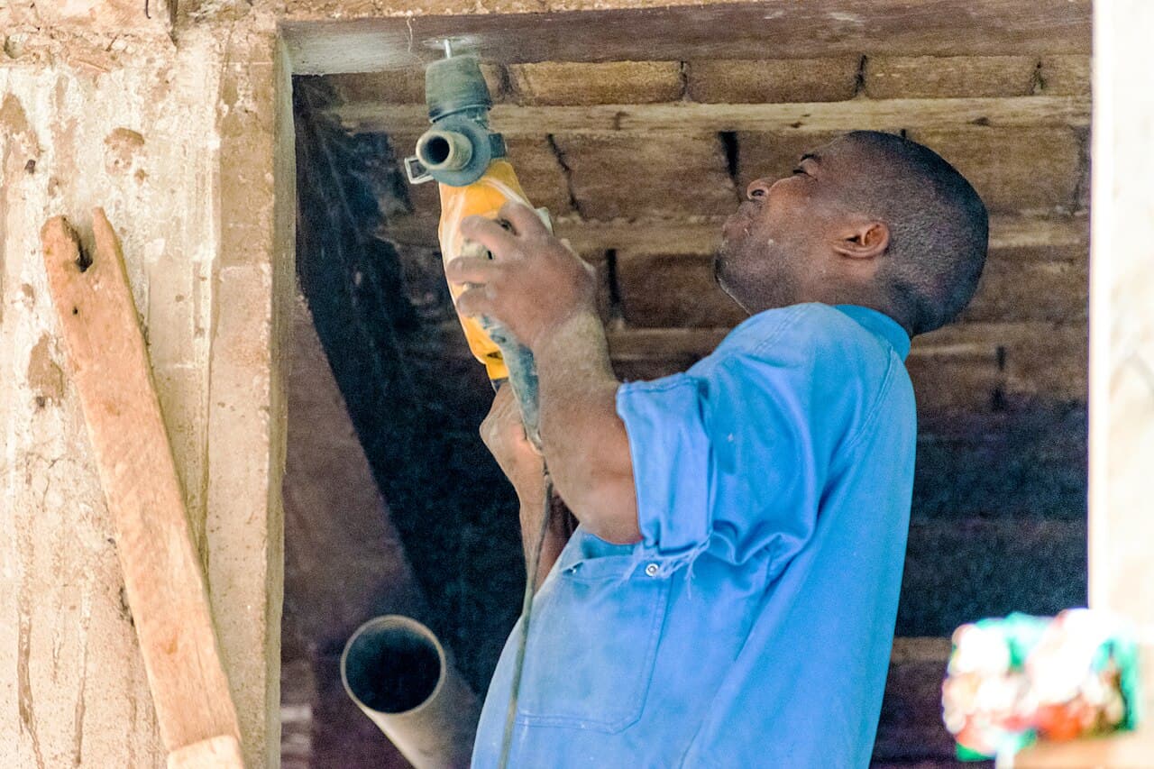 A plumber fitting pipework overhead inside a building.
